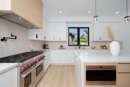 A modern kitchen features top-of-the-line stainless steel appliances and sleek hardwood floors and walls