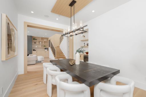 This luxurious dining room features an expansive white table with elegant white chairs, creating a chic and sophisticated atmosphere