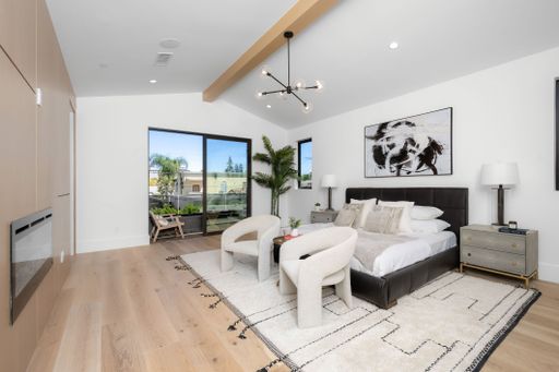 A modern bedroom interior featuring a queen-size bed, a desk and a chair arranged in the corner of the room