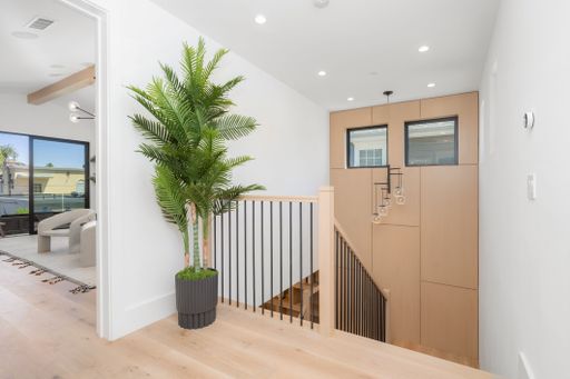 An interior view of a spacious home featuring a grand staircase and a selection of potted plants, creating a warm and inviting atmosphere