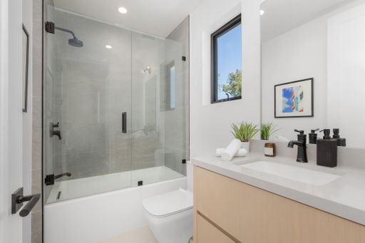 A contemporary styled bathroom featuring a white basin, a white toilet, and a glass shower stall