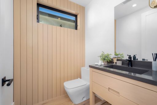 A modern bathroom featuring a stylish black vanity top, placed to the side of a white toilet
