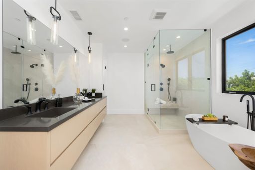 A contemporary bathroom featuring a large window above the vanity sink, as well as a spacious bathtub for a luxurious bathing experience