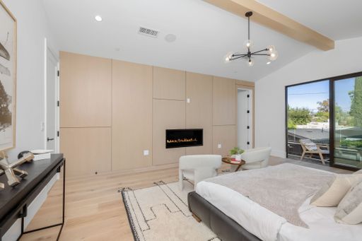 A luxurious king-size bed with a white rug and a selection of decorative pillows, providing a comfortable and inviting atmosphere in a modern bedroom