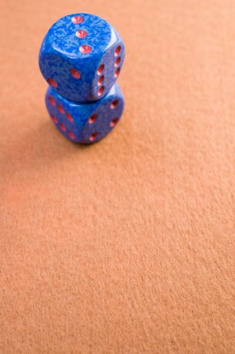 A vertical shot of blue dice on an orange surface under the lights