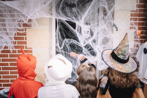 Costumed kids trick-or-treating on halloween behind a web