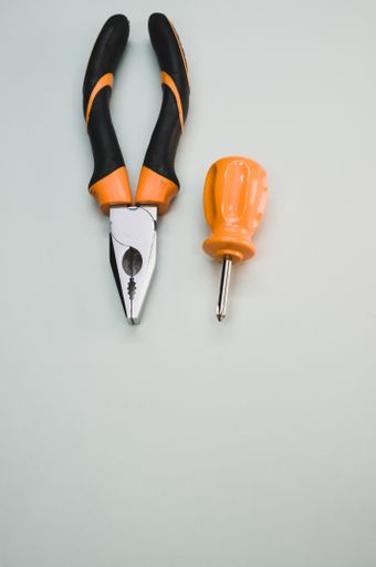 A top view of a small screwdriver with pliers isolated on a gray background