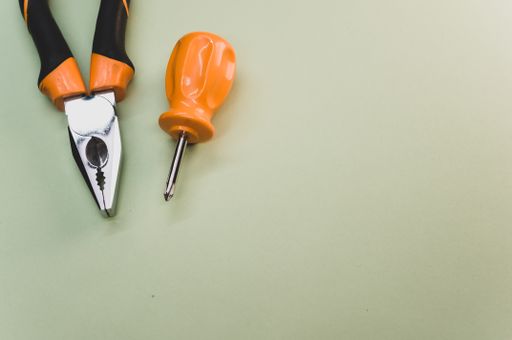 A top view of a small screwdriver and pliers isolated on a green background