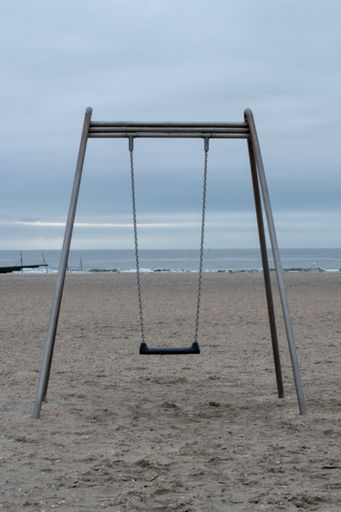 a vertical shot of a  one-seat swing at the Borkum sandy shore