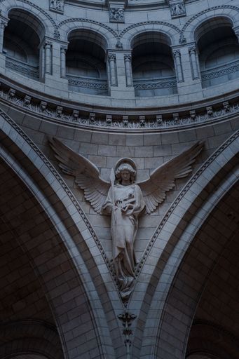 A vertical shot of a beautiful angel statue on the wall inside the Saint Clotilde basilica in Paris