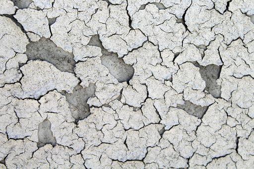 A high angle shot of many cracks on the dry sandy ground - broken heart metaphor