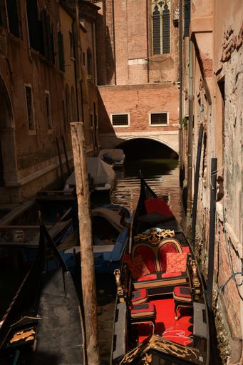 A vertical shot of a traditional narrow and long Venetian rowing boat between the old buildings of Venice, Italy