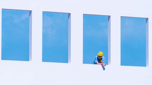 A construction worker looking outside a window of a white skyscraper in Beirut, Lebanon