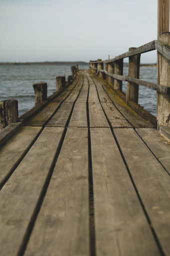 A long wooden pier on the sea and light sky on the horizon