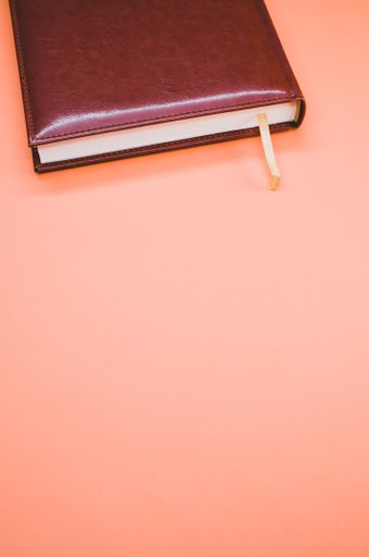 A vertical shot of a brown notebook on pastel peach background with an empty space for a text
