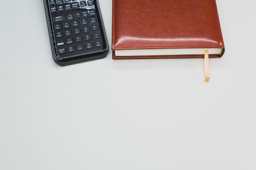A scientific calculator next to a notebook on pastel gray background with an empty space for a text