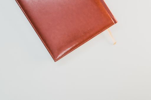 A top view of a brown notebook on pastel gray background with an empty space for a text