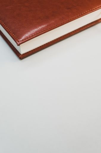 A vertical shot of a brown notebook on pastel gray background with an empty space for a text