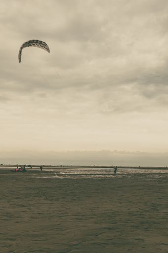 A beautiful shot of a sandy beach on a cloudy sky background with a parachutist in Borkum, Germany