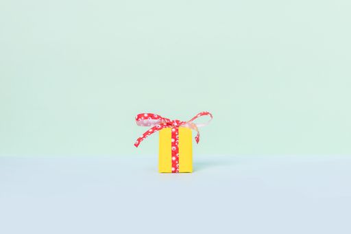 A yellow gift box with red ribbon on a pastel background and space for your text