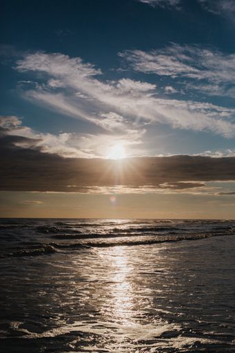 A vertical shot of the sun shining over a calm sea
