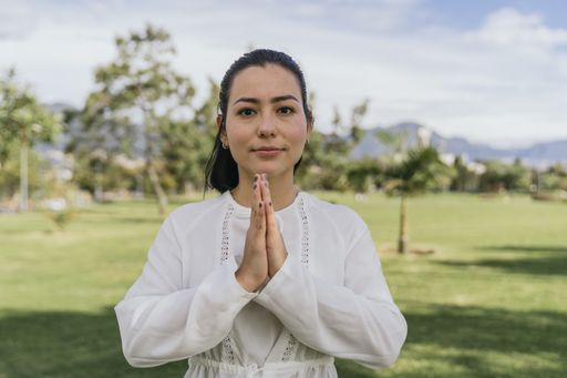 A Hispanic female doing yoga at a park