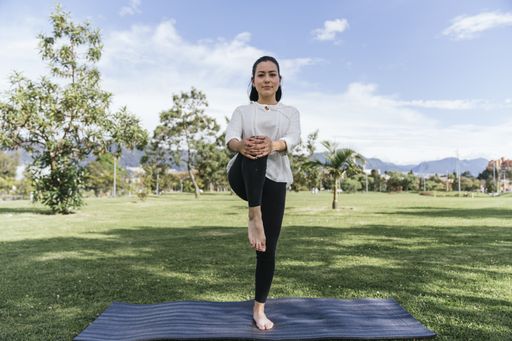 A Hispanic female doing yoga at a park