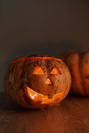 A vertical shot of a jack-o'-lantern for Halloween on the table in a dark room