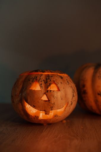A vertical shot of a jack-o'-lantern for Halloween on the table in a dark room