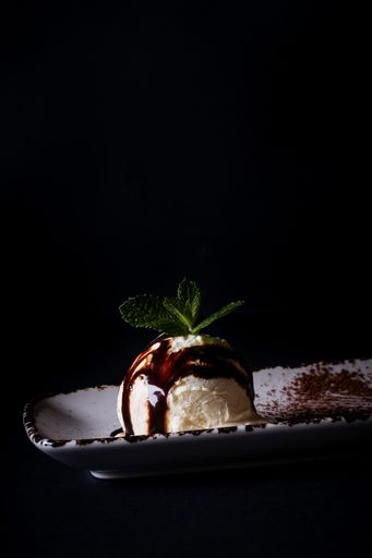 A vertical shot of vanilla ice cream scoop on a plate isolated on black background