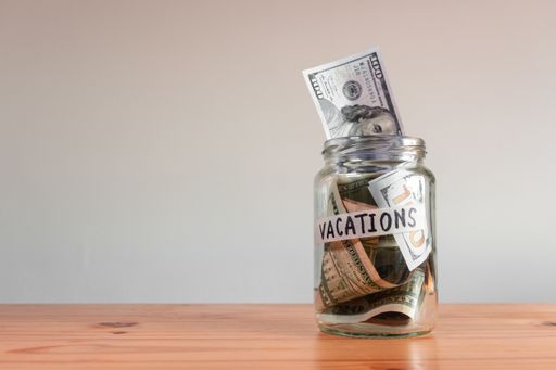 The US Dollar bills in a glass jar labeled "vacations"