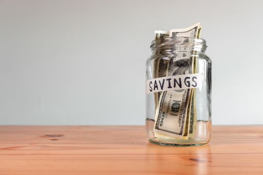 The US Dollar bills in a glass jar labeled "savings"
