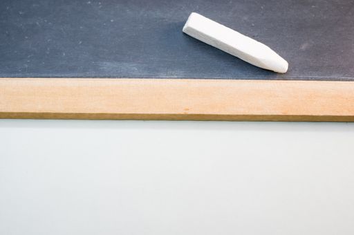 A top-view of a blackboard with white chalk on a white surface
