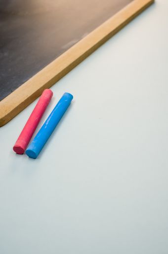 A vertical high angle shot of a blackboard with colorful chalks on a white surface