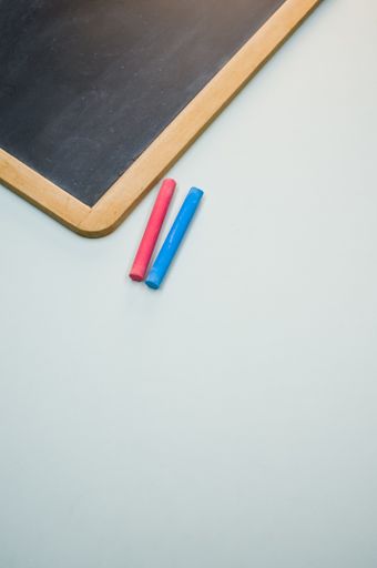 A vertical high angle shot of a blackboard with colorful chalks on a white surface