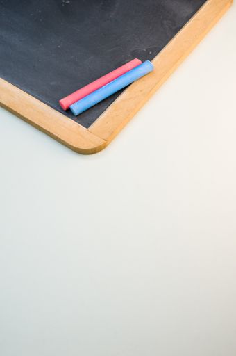 A vertical high angle shot of a blackboard with colorful chalks on a white surface