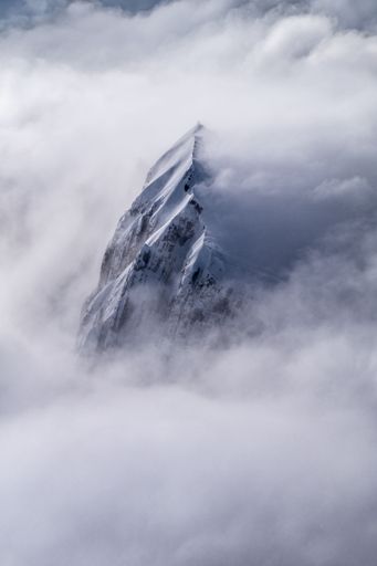 A beautiful mystical view of the snowy mountains covered with dense clouds