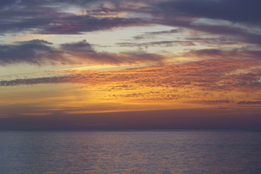 A beautiful shot of the gorgeous orange sky and clouds above the calm sea