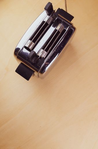 A vertical top view of a black-colored bread toaster on a wooden surface