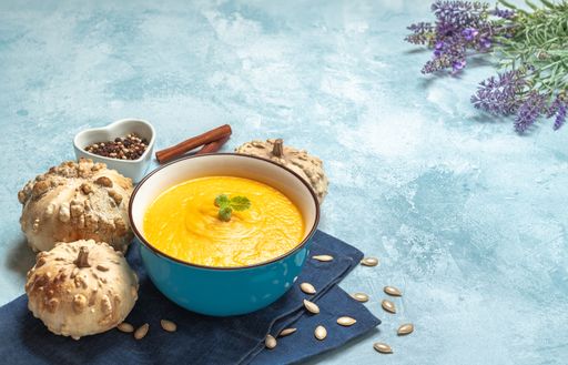 A closeup shot of a pumpkin cream soup surrounded by pumpkins