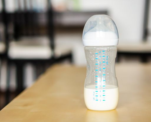 A closeup of milk in a baby bottle on the table with a blurry background
