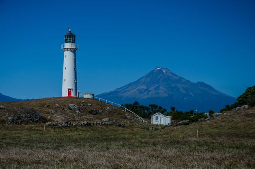 The Cape Egmont Lighthouse with the Mountain Taranaki on the background in Pungarehu, New Zealand