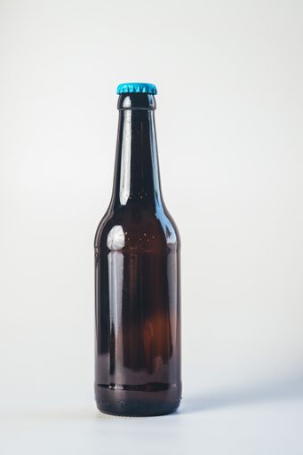 A vertical shot of the beer glass bottle with a blue cap on the white background