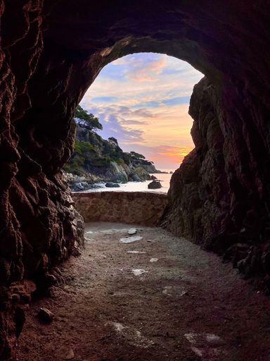A beautiful vertical shot of Lloret de Mar in Spain from a tunnel in the castle with a gorgeous view of the sunrise