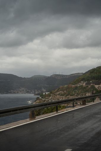 A vertical shot of a road in Croatia on a moody day with clouds and a landscape with hills