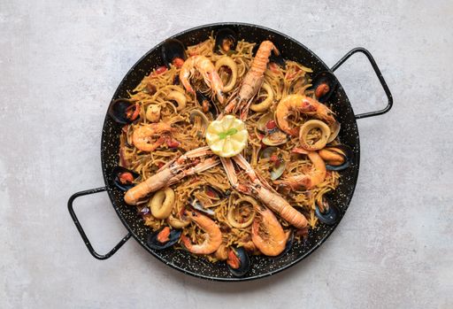 A top view shot of delicious Paella with seafood and onion rings