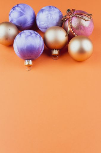 A vertical shot of colorful Christmas ornaments assorted on an orange surface