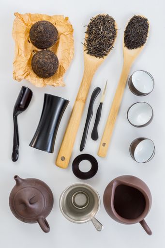 A top view of Chinese tea set and green tea on wooden spoons isolated on white background