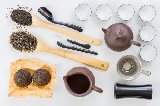 A top view of Chinese tea set and green tea on wooden spoons isolated on white background