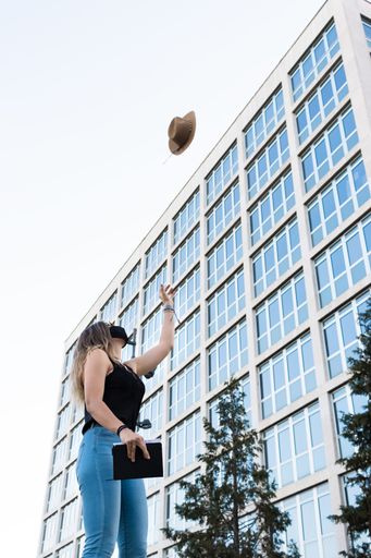 A vertical shot of a young girl throwing her hat in the air
